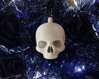 Op de afbeelding: Witte schedelvormige kerstversiering die aan een zwarte kerstboom van tinsel hangt.