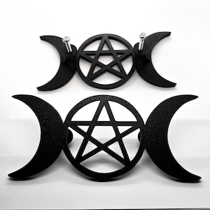 Può includere: Due decorazioni da parete in metallo nero con un pentagramma all'interno di un cerchio, affiancato da lune crescenti. Il pezzo superiore ha viti per il montaggio. Il design è un simbolo Wicca e pagano.