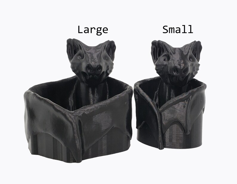 Puede incluir: Dos macetas en forma de murci&eacute;lago impresas en 3D de color negro, una etiquetada como "Grande" y la otra como "Peque&ntilde;a".