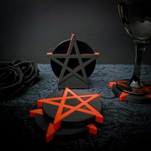 Könnte beinhalten: Satz mit vier schwarzen und orangefarbenen Pentagramm-Untersetzern. Die Untersetzer sind aus einem dicken, strapazierfähigen Material gefertigt und haben ein erhabenes Pentagramm-Design. Die Untersetzer sind perfekt, um Ihre Möbel vor Flecken und Kratzern zu schützen.