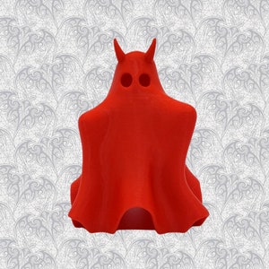 May include: A red, 3D printed ghost figurine with horns. The ghost has a smooth, rounded shape and a simple design.