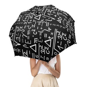 May include: A black umbrella featuring a white print of various mathematical equations, scientific formulas, and geometric symbols covering the entire canopy. The design includes symbols such as pi, square roots, and various algebraic variables.