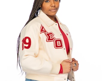 Chaqueta universitaria semicorta de lana color crema Delta Sigma Theta con texto carmesí.