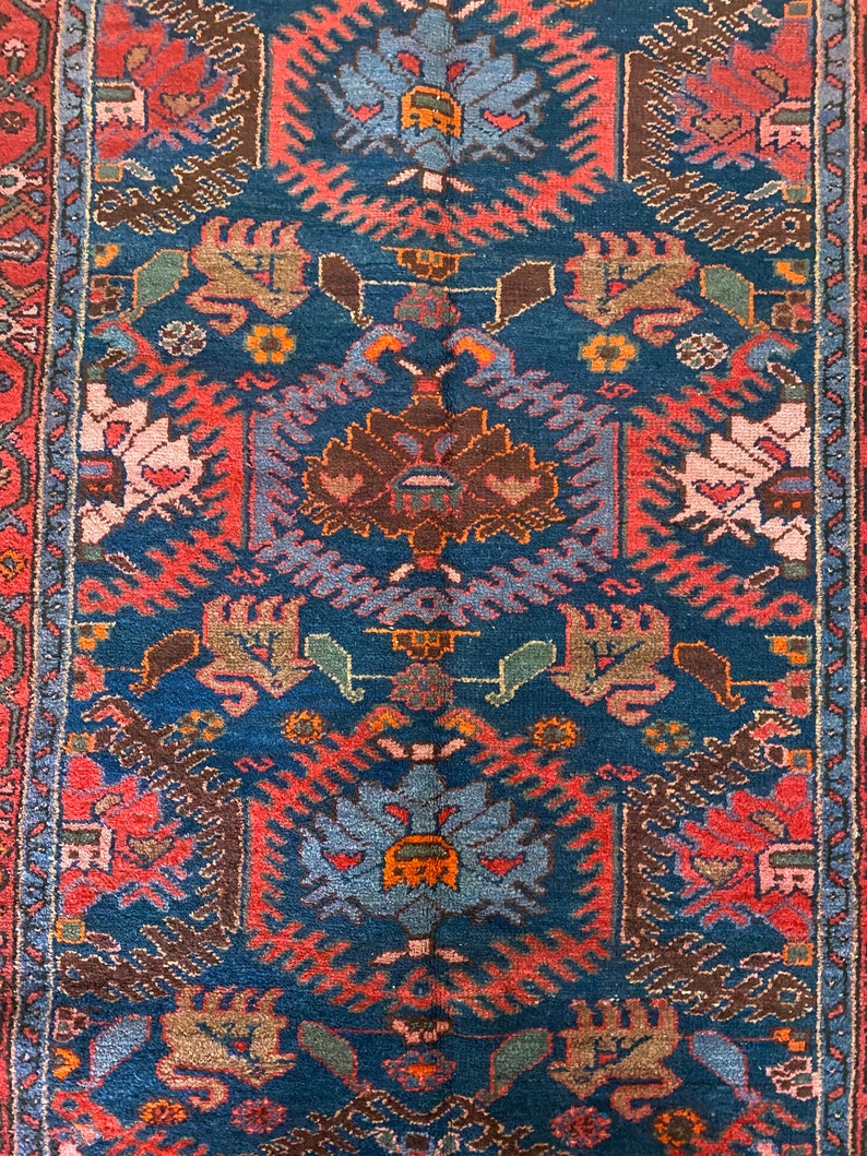 May include: A vintage rug with a blue background and intricate patterns in shades of red, brown, and green. The rug features a central medallion with a floral design and repeating geometric motifs.
