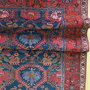 May include: A vintage Persian rug with a deep blue background and intricate red, orange, and brown patterns. The rug has a traditional design with floral motifs and geometric shapes.