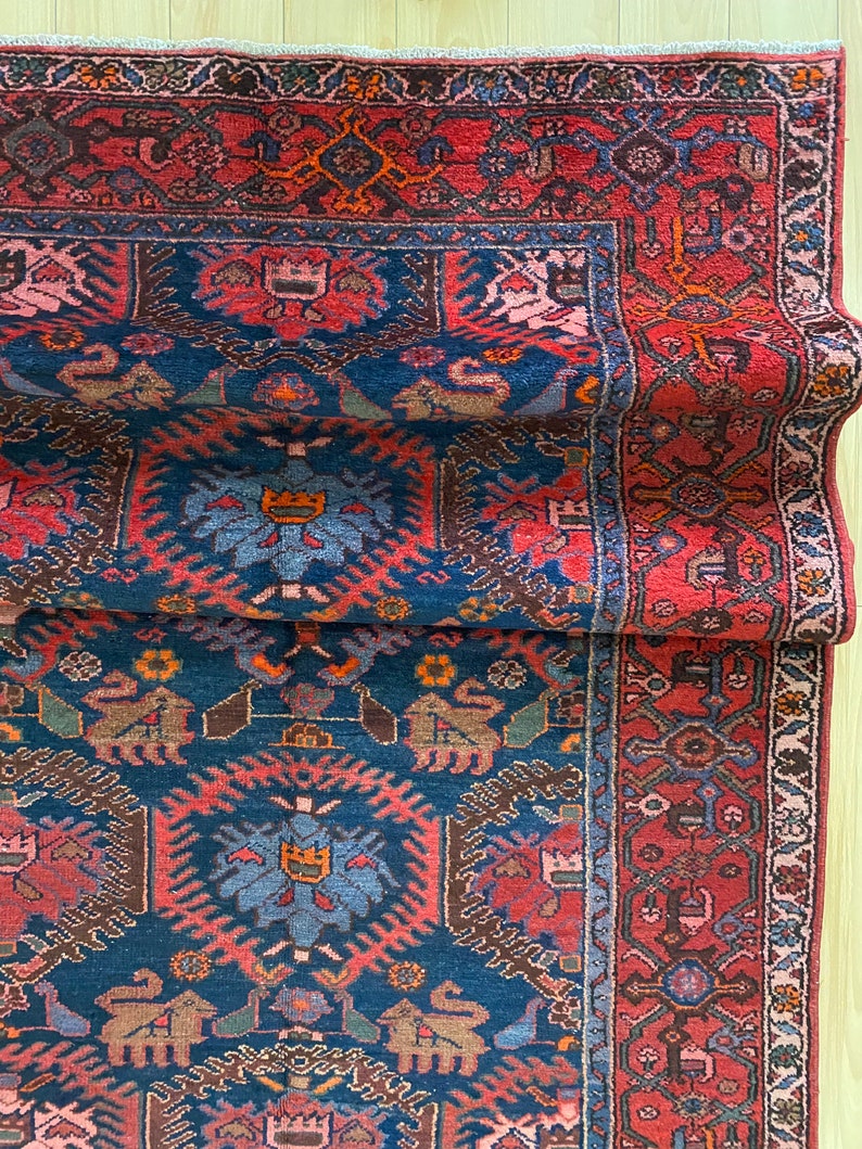 May include: A vintage Persian rug with a deep blue background and intricate red, orange, and brown patterns. The rug has a traditional design with floral motifs and geometric shapes.