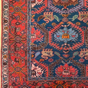 May include: A vintage Persian rug with a deep blue center and a red border. The rug features intricate floral and geometric patterns in shades of red, blue, brown, and beige.