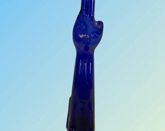 Può includere: Una bottiglia di vetro blu cobalto a forma di gatto. La bottiglia ha un corpo rotondo e un collo lungo e sottile.