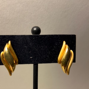 Puede incluir: Un par de pendientes de clip de tono dorado con un diseño de hoja.