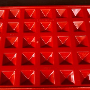 Op de afbeelding: Een felrood plastic Tupperware-dienblad met een herhalend raster van verhoogde, piramidevormige inkepingen. Het oppervlak bevat de in reli&euml;f aangebrachte tekst TUPPERWARE en het nummer 1292-3, met een grote zwarte letter B linksonder.