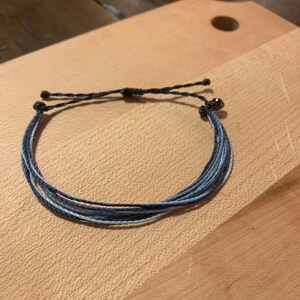 May include: A blue and white friendship bracelet with a silver bead at the end.