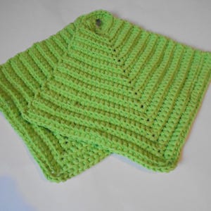 May include: Two lime green, handmade crochet potholders. The potholders are square with a loop for hanging. The crochet stitch creates a textured, ribbed pattern. These kitchen accessories are perfect for protecting hands from hot cookware.