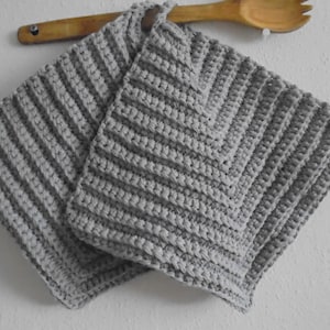 May include: Two grey crocheted pot holders with a striped pattern and a diamond pattern.