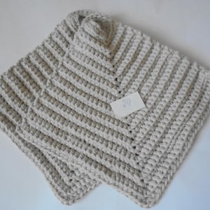 May include: Two beige crocheted squares, one on top of the other, with a handwritten tag that says "29".