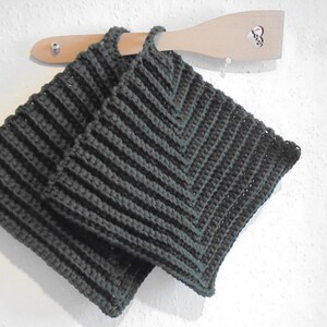 May include: Two dark green crocheted pot holders with a textured pattern. The pot holders are hanging on a wooden spoon.