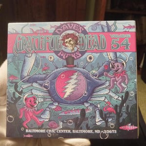 May include: A box set featuring artwork with a crab, bears, and the Grateful Dead logo. The design includes the text "Dave's Picks Volume 54" and "Baltimore Civic Center, Baltimore, MD 3/26/73". The artwork is colorful with a sea theme.
