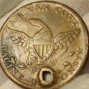 May include: A brass token with an eagle and the text "A.B. Van Cott Racine - Wis. Co."
