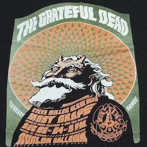 May include: Black t-shirt featuring a vintage concert poster design. The design includes the text "THE GRATEFUL DEAD" in white, a Santa Claus-like figure, and concert details for Steve Miller Blues Band, Moby Grape, and Avalon Ballroom.