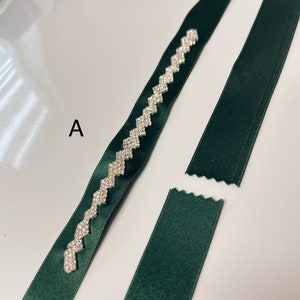 May include: Two pieces of dark green ribbon, one with a decorative row of silver rhinestones in a zig-zag pattern. The ribbon with the rhinestones is labeled with the letter "A".