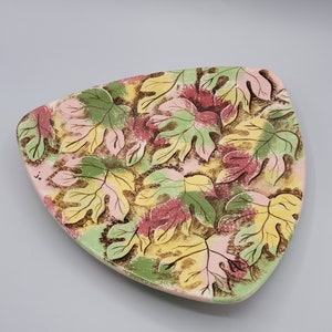 May include: A triangular ceramic serving dish with a leaf pattern in shades of green, pink, yellow, and brown.