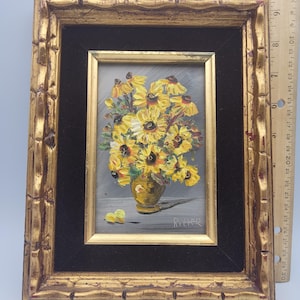 May include: A framed oil painting of yellow sunflowers in a gold vase. The painting is set against a gray background and framed in a gold, ornate frame. The frame measures approximately 10 inches in height.