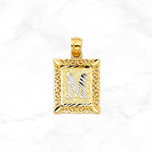 May include: Gold pendant with a square frame and a white letter M inside. The frame has a detailed design.