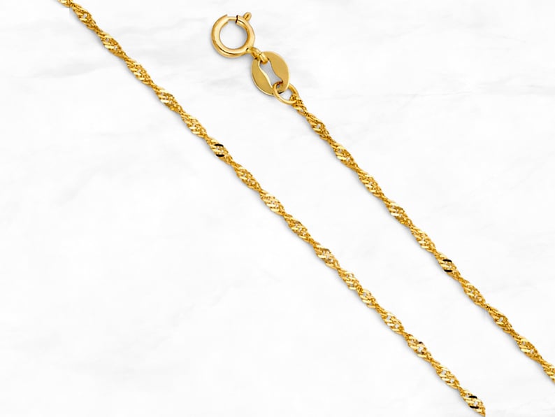 May include: A gold chain necklace with a twisted rope design. The chain is about 18 inches long and has a lobster claw clasp.