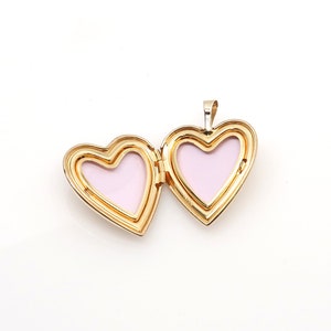 May include: A gold heart-shaped locket pendant with a pink interior. The locket is open, revealing the two halves of the heart.