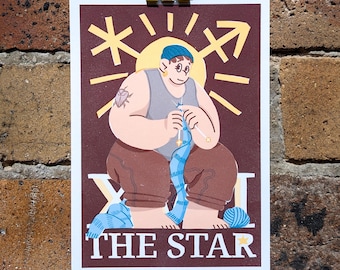 May include: A rectangular art print on a dark brown background featuring a person knitting with blue yarn. The person wears a blue beanie, gray tank top, and brown pants. Above them is a yellow sun symbol and the text THE STAR in white letters.