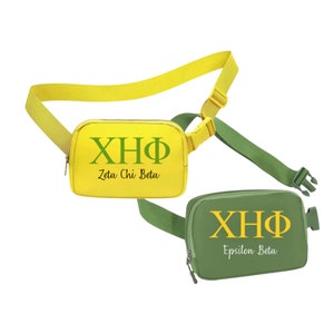 Peut inclure: Deux sacs banane avec des sangles réglables. L'un est jaune avec des lettres vertes qui disent "XHQ Zeta Chi Beta". L'autre est vert avec des lettres jaunes qui disent "XHQ Epsilon Beta".