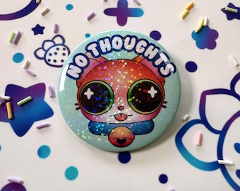 Puede incluir: Un botón redondo con una ilustración de gato de dibujos animados. El gato tiene ojos grandes y brillantes y el texto "NO THOUGHTS" en blanco. El botón es azul claro con un efecto holográfico, y el gato es naranja, rosa y azul.