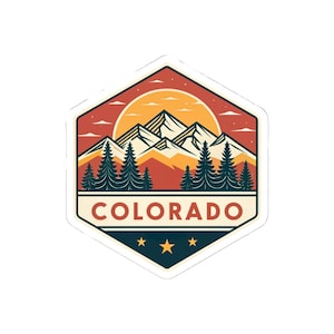May include: A hexagonal sticker featuring a Colorado mountain landscape. The design includes a sunset, pine trees, and mountains, with the word "COLORADO" at the bottom. Three stars are below the text.