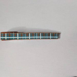 May include: A roll of blue and orange plaid ribbon with a white background.