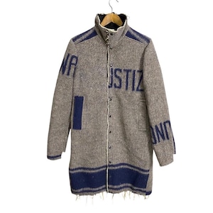 May include: A grey wool jacket with blue trim and the words "JUSTIZ" and "UND" on the front and back. The jacket has a high collar and a button closure.