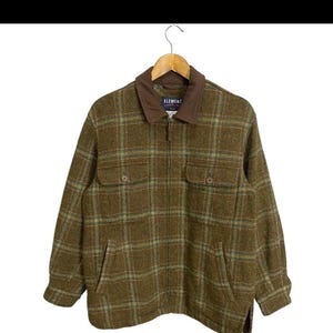 May include: A brown and green plaid jacket with a brown corduroy collar and a zip closure. The jacket has two flap pockets on the front and a label that reads "ELEMENT" on the left side of the collar.