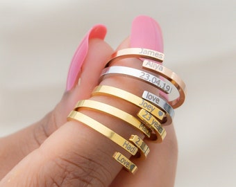 May include: A stack of gold and silver rings with personalized engravings. The engravings include names, dates, and words like "love" and "Joey".