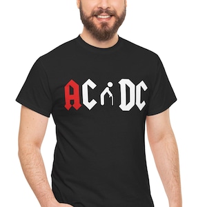 Può includere: Una t-shirt nera a maniche corte con una stampa grafica sul petto. Il design mostra il testo AC/DC in un carattere stilizzato, con la lettera A in rosso e le lettere C, D e C in bianco. Un'icona bianca a forma di omino stilizzato sostituisce la barra.