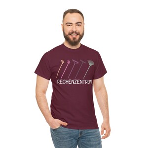 K&ouml;nnte beinhalten: Ein maroonfarbenes T-Shirt mit einer Grafik von f&uuml;nf verschiedenen Rechen in einer Reihe. Der Text "RECHENZENTRUM" ist unter den Rechen gedruckt.