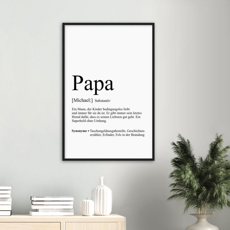 Może przedstawiać: Czarno-biała, drukowana grafika ścienna z definicją słowa "Papa" w języku niemieckim. Definicja brzmi: "Mężczyzna, kt&oacute;ry kocha swoje dzieci bezwarunkowo i zawsze jest dla nich. Zawsze oddaje swoją ostatnią koszulę, aby upewnić się, że jego bliscy mają się dobrze. Superbohater bez peleryny."