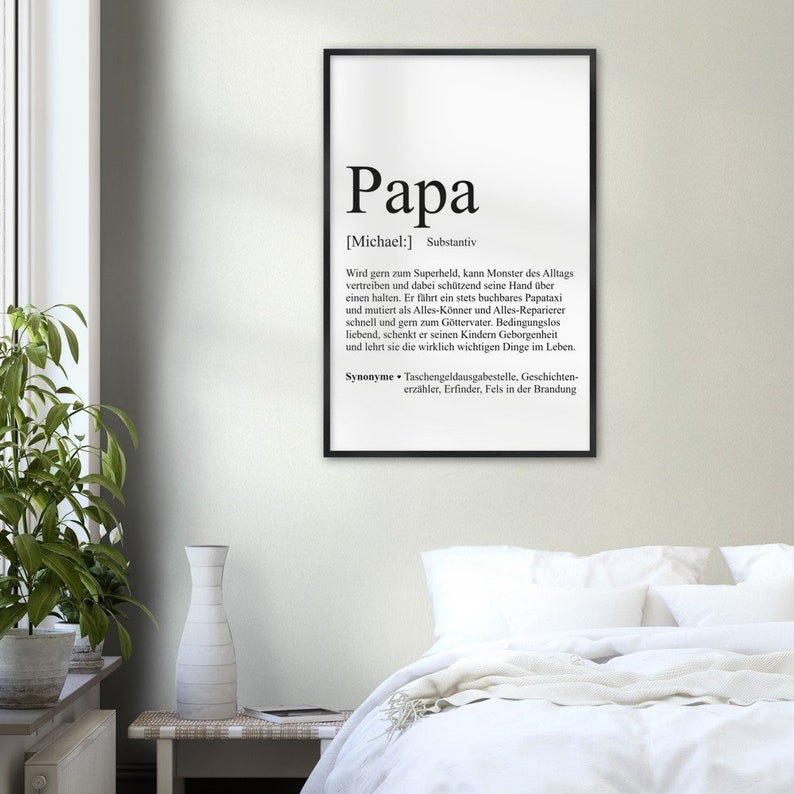 May include: Black and white printable wall art with a definition of the word "Papa" in German. The definition describes a father as a superhero, protector, and provider.