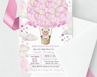 Op de afbeelding: Een roze en witte babyshower-uitnodiging met een teddybeer in een luchtballon. De uitnodiging luidt "Baby Rue is on the way" en bevat de datum, tijd en locatie van de babyshower. Er staat ook "We can bearly wait" op.