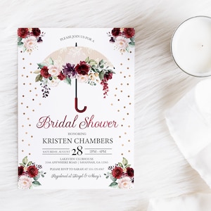 May include: Bridal shower invitation with a watercolor illustration of a white lace umbrella with burgundy and pink flowers. The text reads "Please join us for a Bridal Shower honoring Kristen Chambers, Saturday, August 28, 2PM-4PM, Lakeview Clubhouse, 5144 Anywhere Road, Savannah, GA 12345, Please RSVP to Sarah at 555.123.4567, Registered at Target & Macy's".