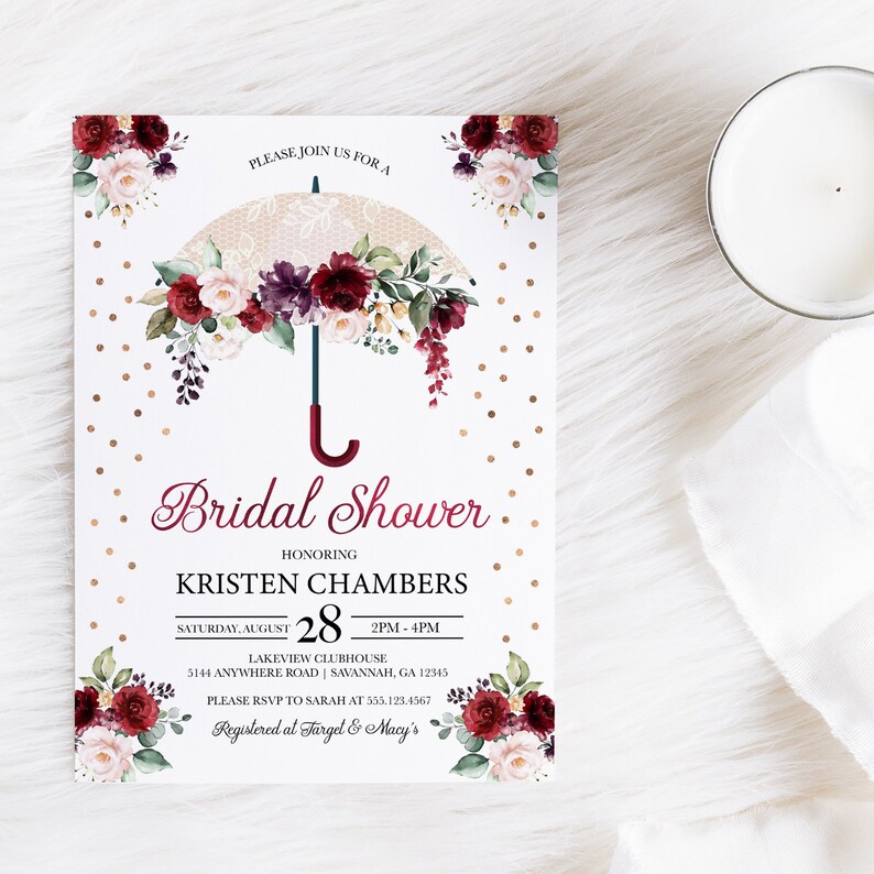 May include: Bridal shower invitation with a watercolor illustration of a white lace umbrella with burgundy and pink flowers. The text reads "Please join us for a Bridal Shower honoring Kristen Chambers, Saturday, August 28, 2PM-4PM, Lakeview Clubhouse, 5144 Anywhere Road, Savannah, GA 12345, Please RSVP to Sarah at 555.123.4567, Registered at Target & Macy's".