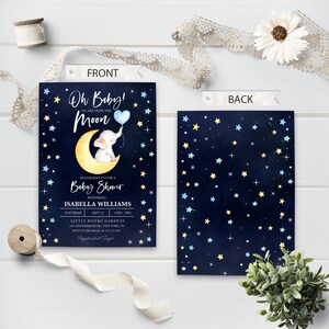 Puede incluir: Una invitaci&oacute;n de baby shower con un elefante azul y amarillo sosteniendo un globo azul frente a una luna creciente amarilla. El fondo es azul oscuro con estrellas blancas, amarillas y azules. El texto de la invitaci&oacute;n dice "Oh Baby! We are over the Moon" y "Please join us for a Baby Shower honoring Isabella Williams".