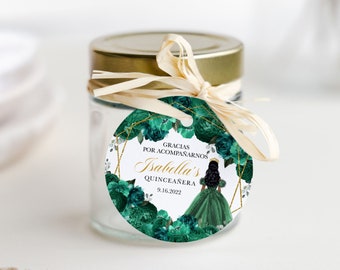 May include: A round favor tag with a green and gold floral design. The tag features a silhouette of a woman in a green dress and crown. The text on the tag reads "Gracias por acompañarnos Isabella's Quinceañera 9.16.2022".
