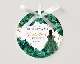 May include: Round ornament with a white ribbon, featuring a teal floral design and gold geometric accents. The ornament includes the text "Gracias Por Acompañarnos Isabella's Quinceañera 9.16.2022" and an illustration of a girl in a green gown.
