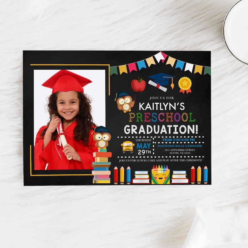 May include: A preschool graduation invitation featuring a photo of a smiling child in a red graduation gown and cap. The invitation has a black chalkboard design with colorful text and illustrations, including owls, books, and a school bus.