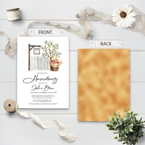 May include: A white invitation card with a watercolor illustration of a picket fence, a potted plant, and a sign that says "Housewarming". The text on the card reads "Please join us for a Housewarming hosted by Joshua Brown, Saturday, November 25th at 5PM, The Brown Residence, 200 Anywhere Rd,  [City, State]  Please RSVP by November 11th, [Phone Number] or [Email Address] Join us for appetizers, drinks & games to celebrate!"