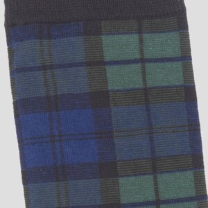 May include: A knit sock featuring a dark blue, forest green, and black plaid pattern. The top of the sock has a solid black ribbed cuff. The fabric has a visible woven texture throughout, showcasing a classic tartan design in deep, cool tones.