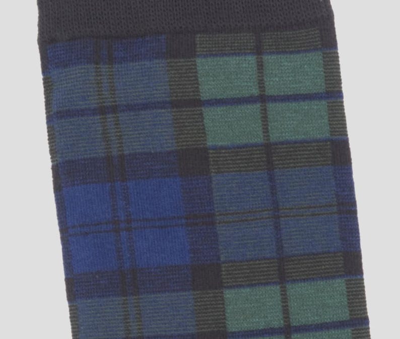 May include: A knit sock featuring a dark blue, forest green, and black plaid pattern. The top of the sock has a solid black ribbed cuff. The fabric has a visible woven texture throughout, showcasing a classic tartan design in deep, cool tones.